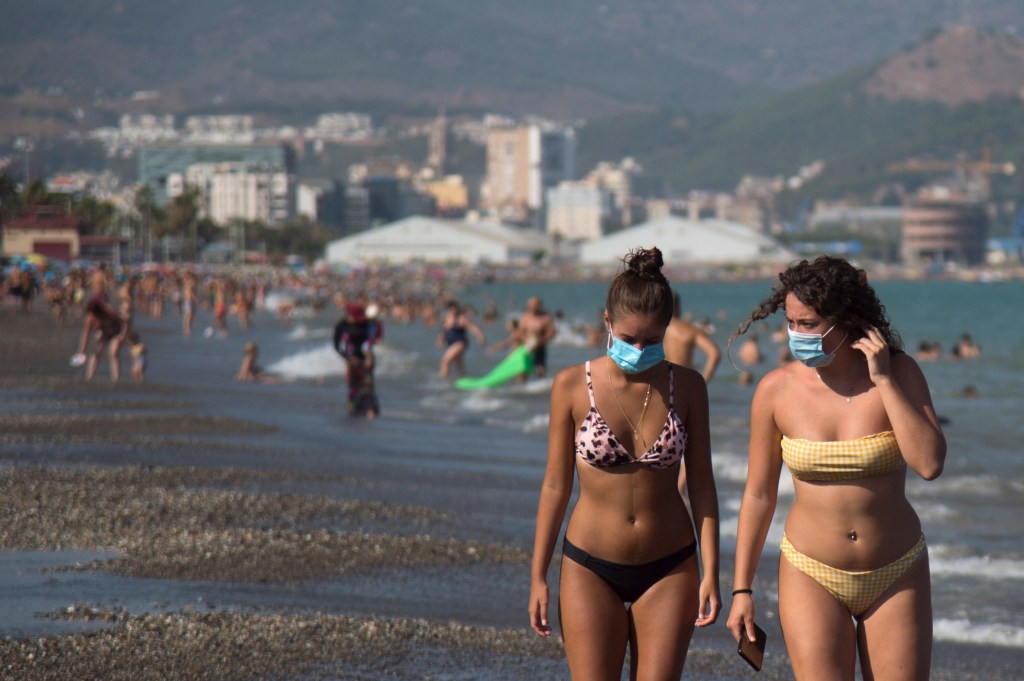 Mulheres com máscaras andam em praia em Málaga, Espanha. 22/07/2020