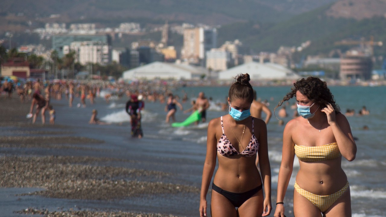 Mulheres com máscaras andam em praia em Málaga, Espanha. 22/07/2020