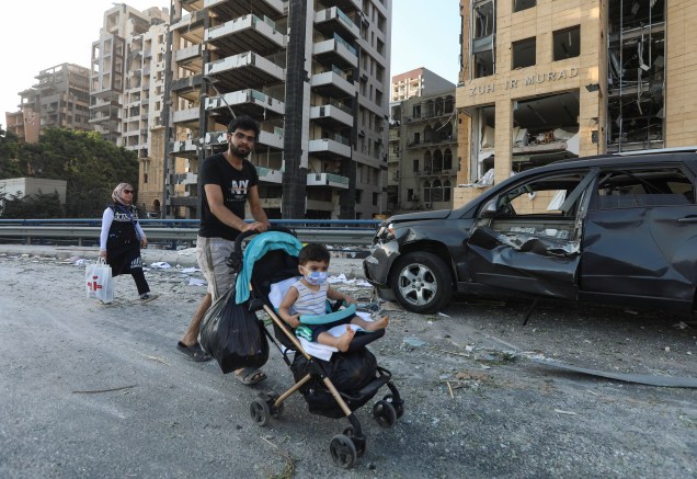 Homem passeia com criança em área próxima ao local da explosão na capital libanesa - 05/08/20020