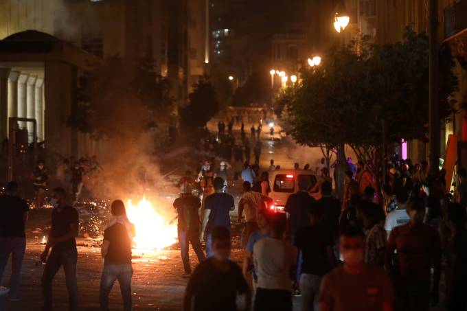 Demonstrators stand near burning fire during a protest near parliament in Beirut