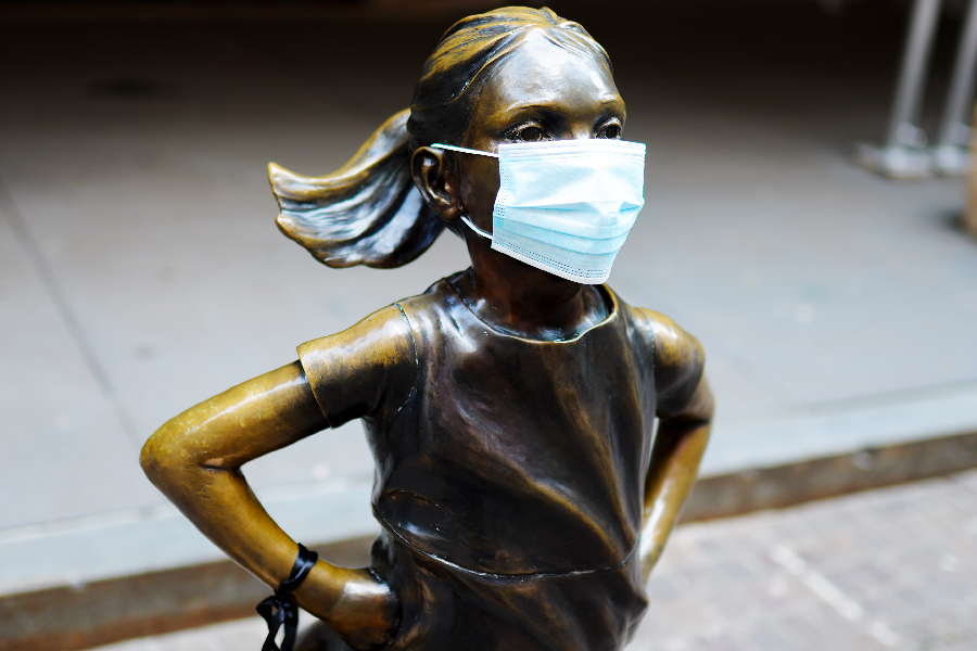 Fearless girl art installation stands in front of the New York Stock Exchange wearing a mask