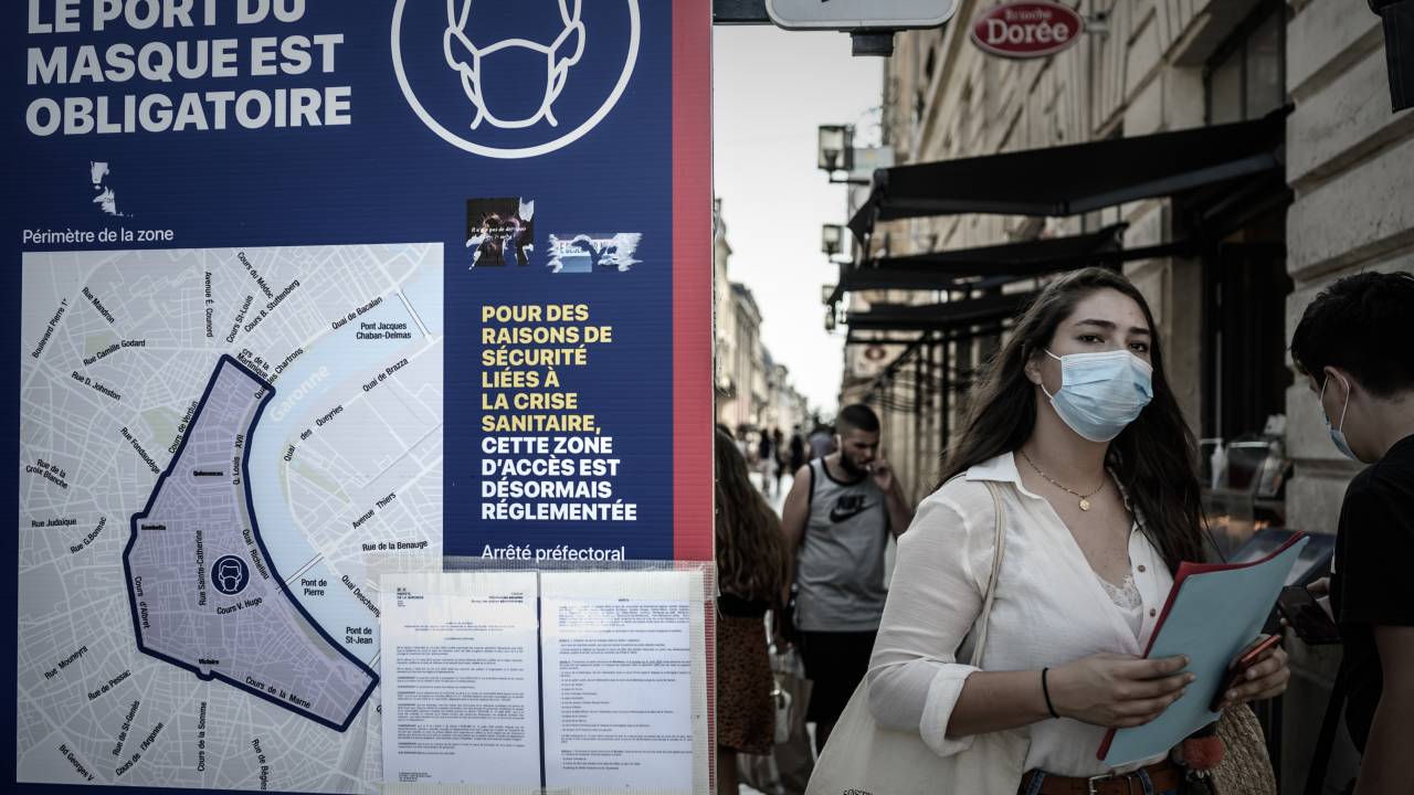 Mulher vista com máscara ao lado de placa que indica obrigatoriedade de proteção facial, em Bordeaux, França. 16/09/2020