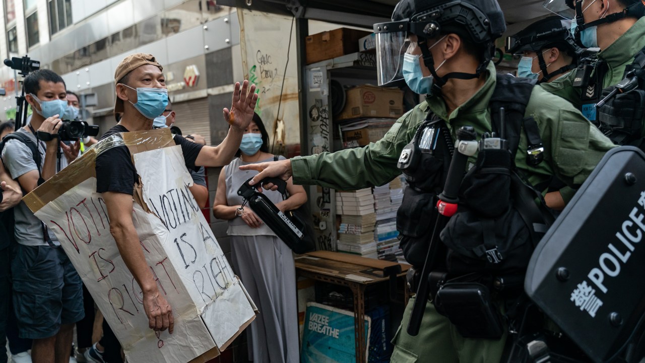 Manifestante com um cartaz escrito "O voto é um direito" é afastado por um policial durante manifestação em Hong Kong