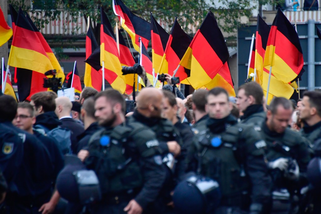 Apoiadores do AfD, da extrema direita, seguram bandeiras da Alemanha atrás de barreira policial durante manifestação em Chemnitz. 01/09/2018