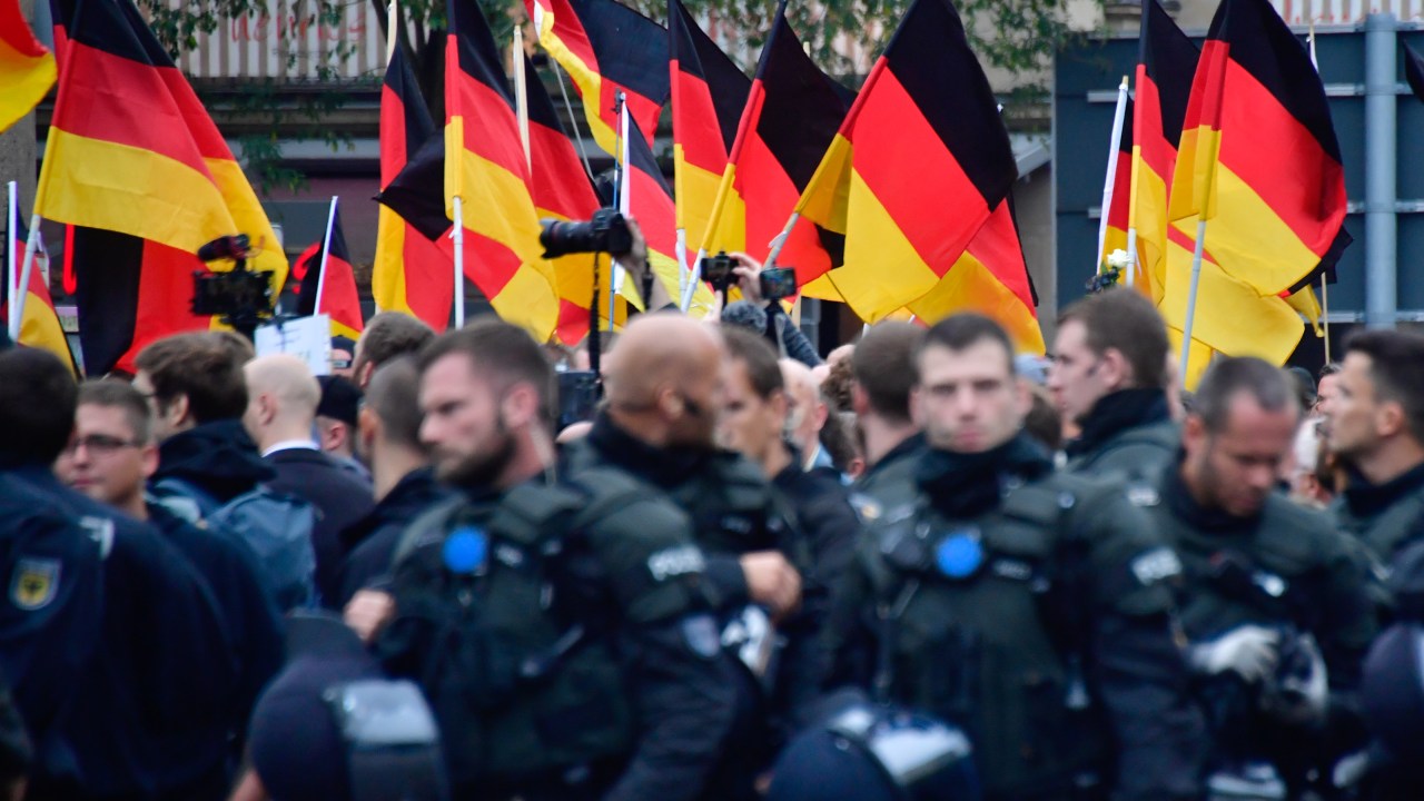 Apoiadores do AfD, da extrema direita, seguram bandeiras da Alemanha atrás de barreira policial durante manifestação em Chemnitz. 01/09/2018