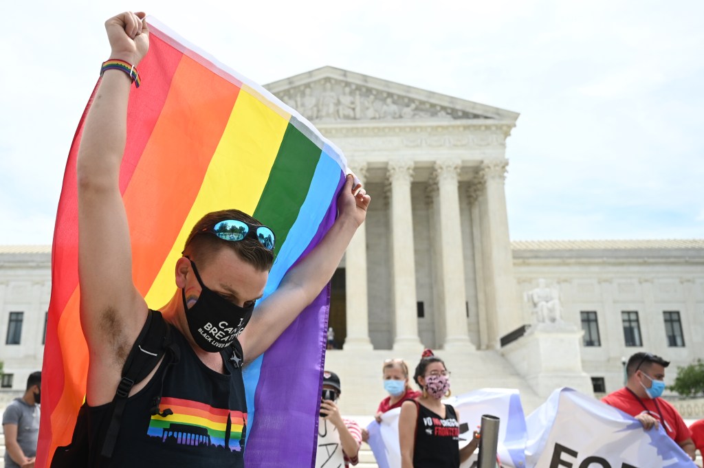 Homem segura bandeira da comunidade LGBTQ+ na frente da Suprema Corte dos Estados Unidos, em Washington. 15/06/2020