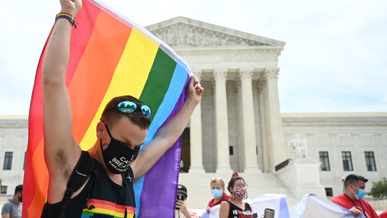 Homem segura bandeira da comunidade LGBTQ+ na frente da Suprema Corte dos Estados Unidos, em Washington. 15/06/2020