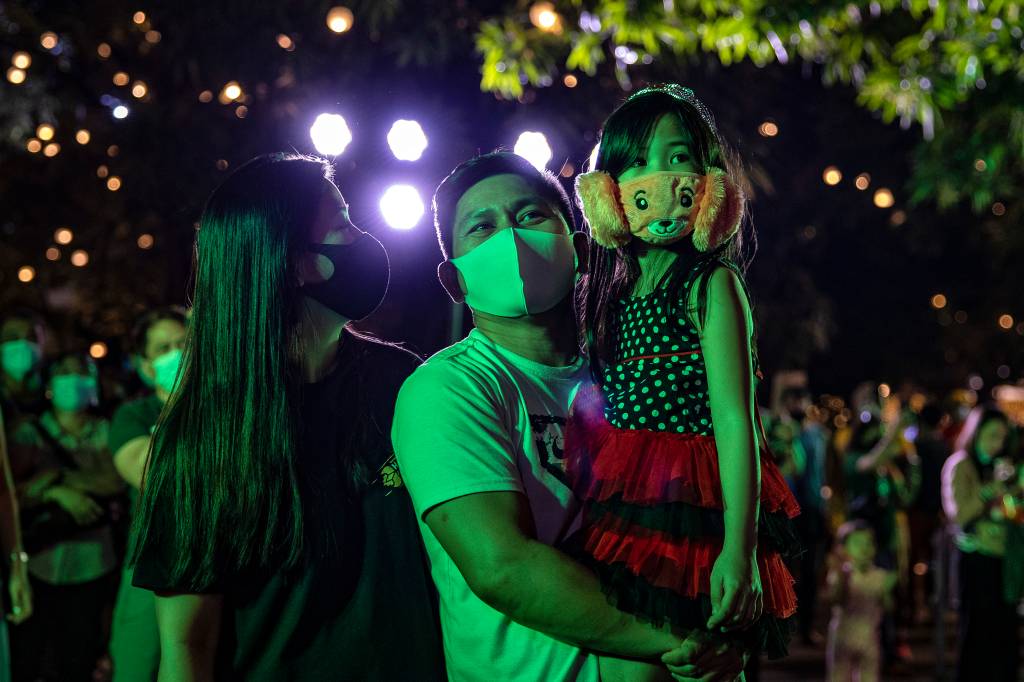 Família em Manila, nas Filipinas, acompanham queimas de fogos na virada para 2021