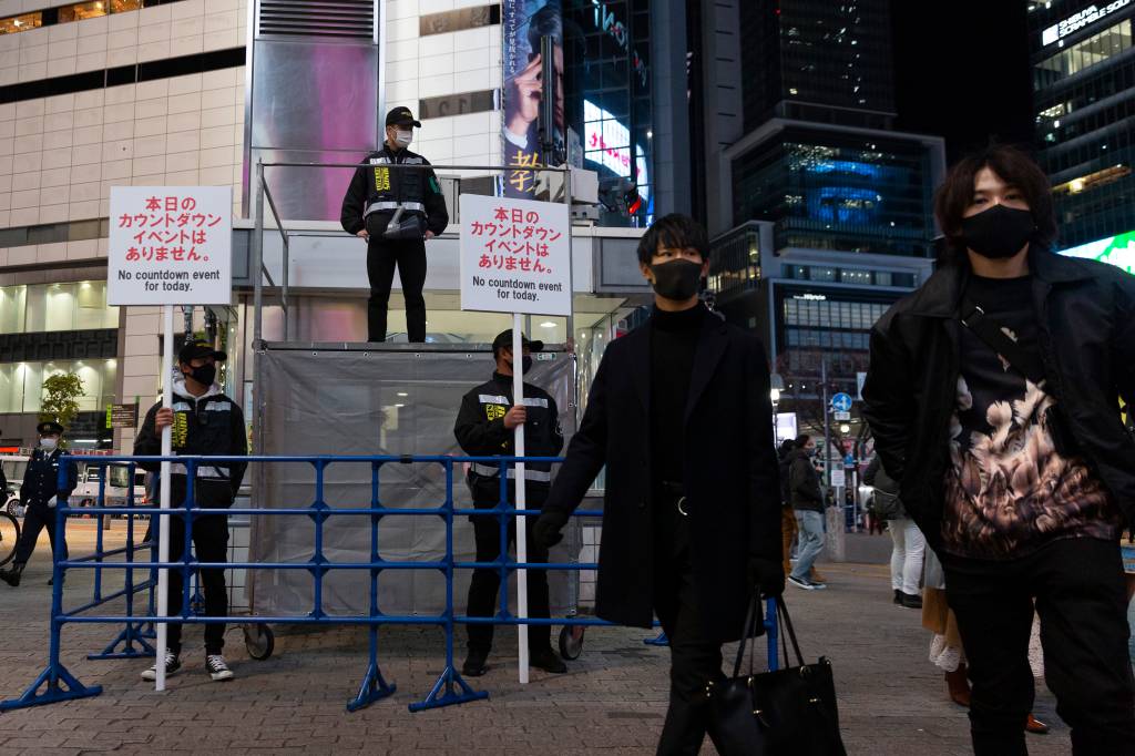 Policiais alertam em placas, em Tóquio, o cancelamento da festa de Ano Novo (31/12/2020)