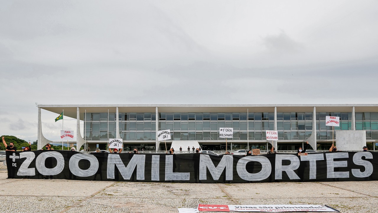Manifestantes seguram uma faixa com os dizeres "Mais de 200.000 mortos" durante um protesto em homenagem às duzentas mil pessoas mortas pelo coronavírus, em frente ao Palácio do Planalto, em Brasília -