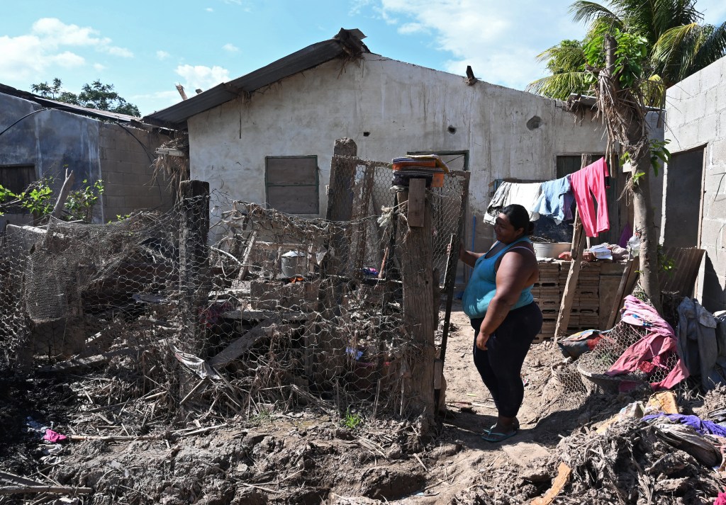Mulher parada em frente a uma casa danificada pelos furacões Eta e Iota em 2020, no município de La Lima, Departamento de Cortes, Honduras. 08/01/2021