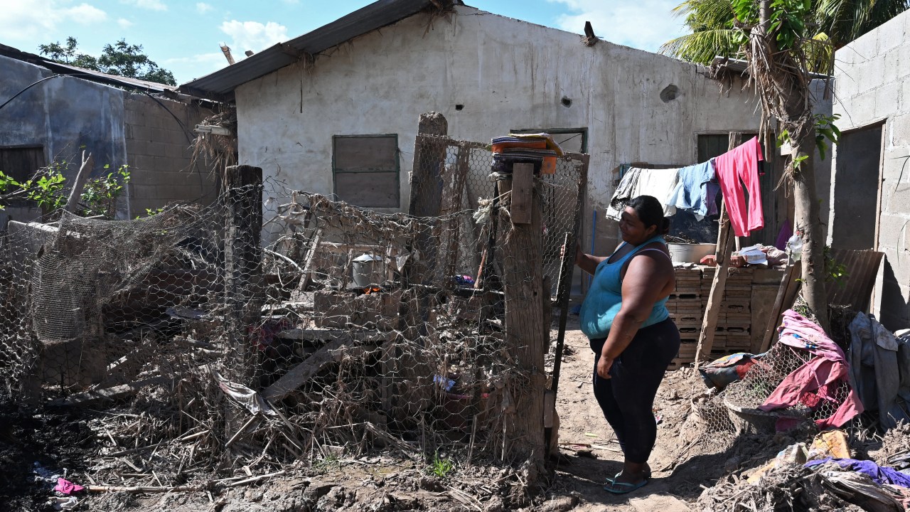 Mulher parada em frente a uma casa danificada pelos furacões Eta e Iota em 2020, no município de La Lima, Departamento de Cortes, Honduras. 08/01/2021