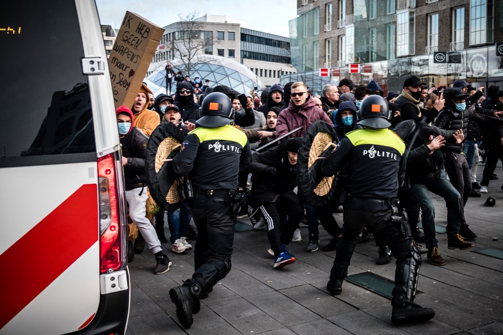Protesters clash against Dutch anti-riot police officers during a demonstration against coronavirus restrictions on 18 Septemberplein square in Eindhoven, the Netherlands, on January 24, 2021. (Photo by ROB ENGELAAR / ANP / AFP) / Netherlands OUT