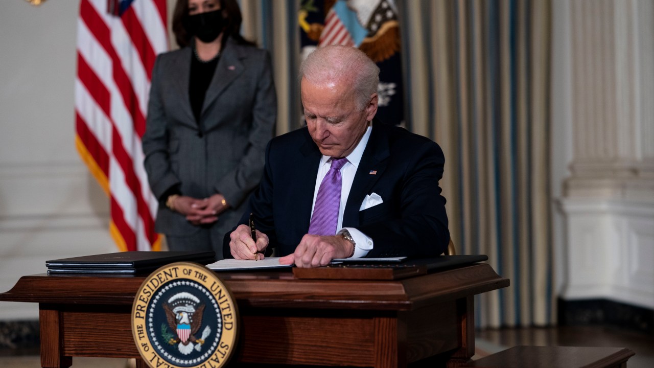 WASHINGTON, DC - JANUARY 26: (L-R) Vice President Kamala Harris looks on as U.S. President Joe Biden signs executives orders related to his racial equity agenda in the State Dining Room of the White House on January 26, 2021 in Washington, DC. President Biden signed executive actions Tuesday on housing and justice reforms, including a directive to the Department of Justice to end its use of private prisons. Doug Mills-Pool/Getty Images/AFP
