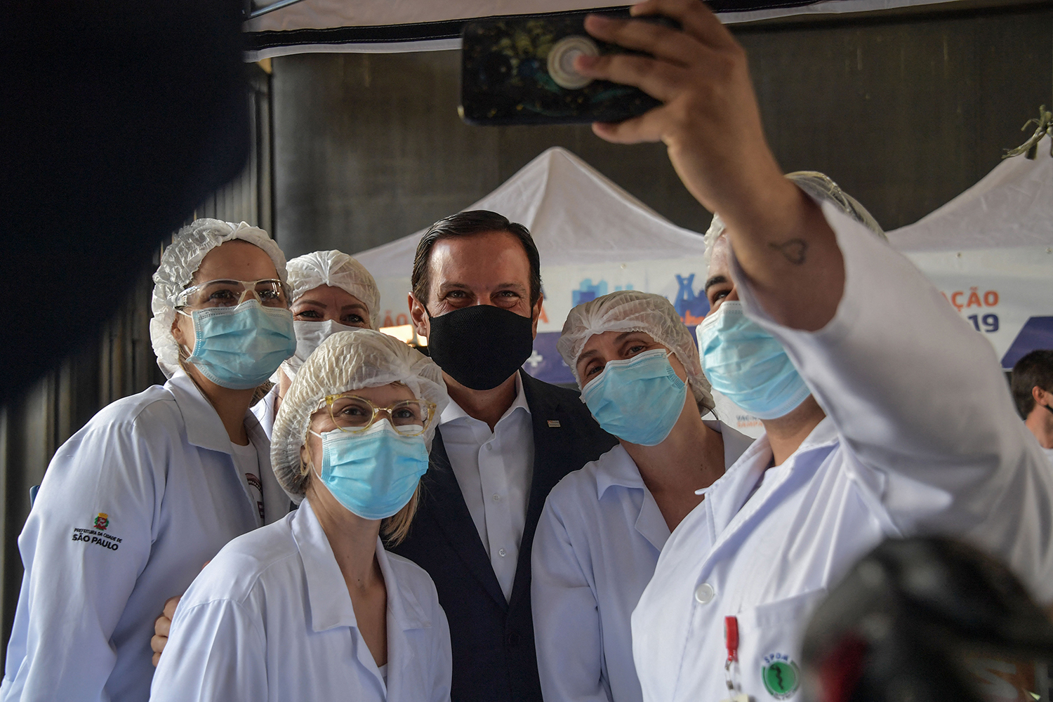 João Doria posa para uma foto com profissionais de saúde em uma unidade no centro de vacinação localizado no Estádio do Pacaembu -