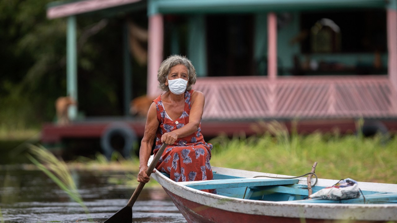 Olga D'arc Pimentel, 72, rows a boat to be vaccinated by a health worker with a dose of Oxford-AstraZeneca COVID-19 vaccine in the Nossa Senhora Livramento community on the banks of the Rio Negro near Manaus, Amazonas state, Brazil on February 9, 2021. (Photo by MICHAEL DANTAS / AFP)