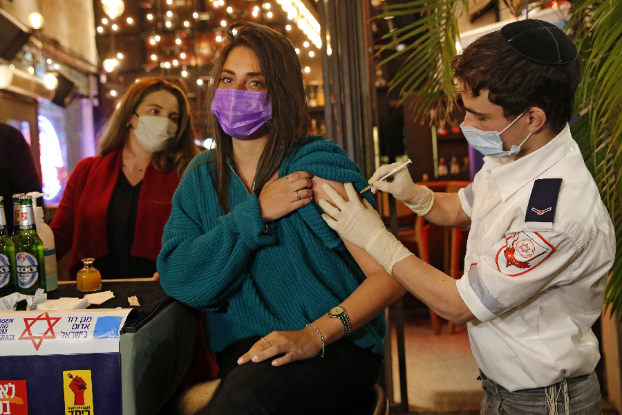 A health worker administers the COVID-19 vaccine to an Israeli at a bar in the coastal city of Tel Aviv on February 18, 2021 -