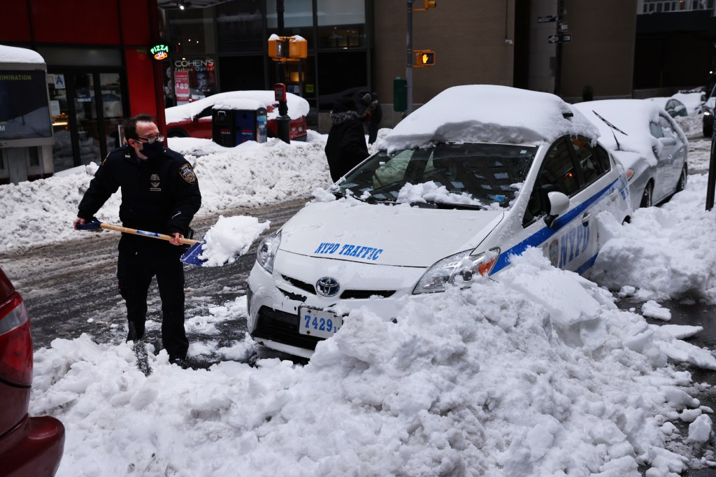 Policial retira neve de viatura em Manhattan, Nova York. 02/02/2021