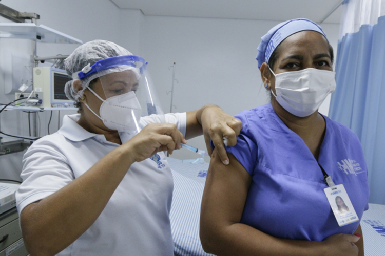 Uma profissional da linha de frente sendo vacinada contra a Covid-19, em Recife -