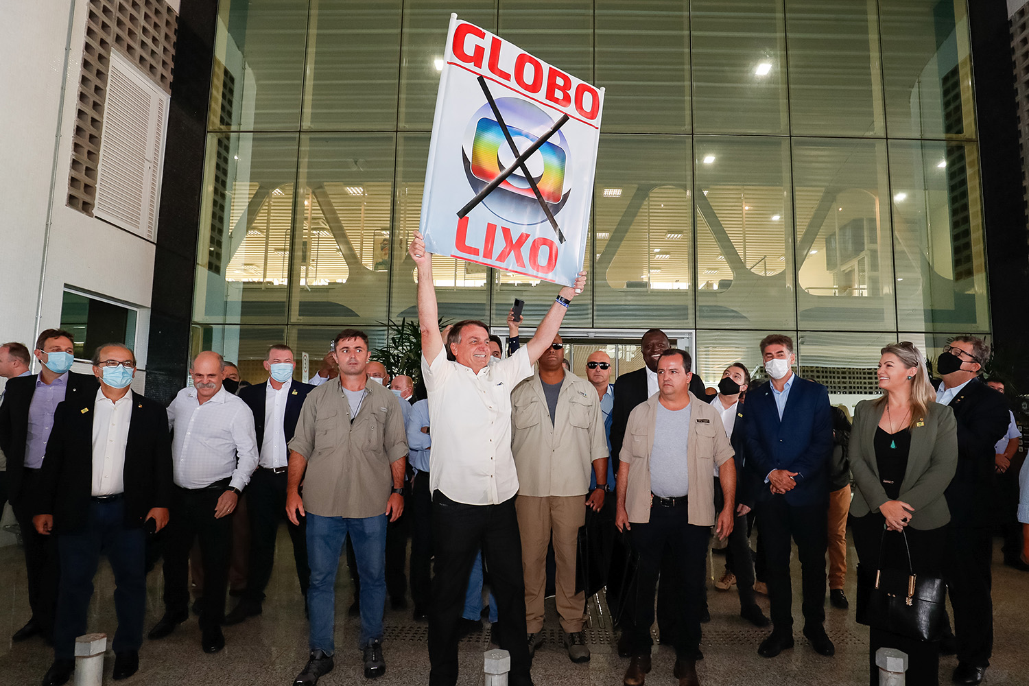 Jair Bolsonaro, cumprimenta os populares presentes no aeroporto e segura placa contra a Rede Globo, em Cascavel/PR -