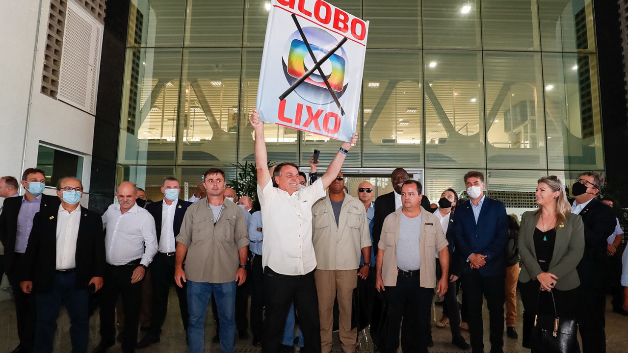 Jair Bolsonaro, cumprimenta os populares presentes no aeroporto e segura placa contra a Rede Globo, em Cascavel/PR -