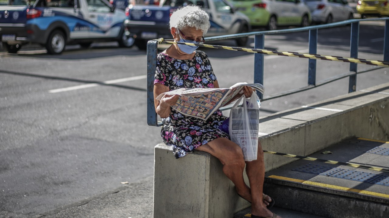 Mulher com máscara de proteção lê jornal na Tijuca, Rio de Janeiro. 13/05/2020