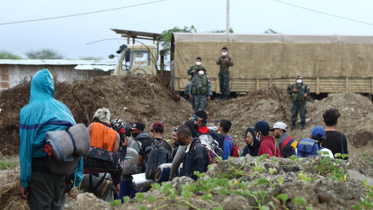 CANTON HUAQUILLAS, ECUADOR - JANUARY 29: Peruvian military officers stand guard as Venezuelan migrants attempt to cross the border to Peru on January 29, 2021 in Cantón Huaquillas, Ecuador. Peruvian Army deployed in the past week 50 armored vehicles to patrol the Peruvian-Ecuadorian border of Zarumilla river and prevent Venezuelan migrants from entering the country amid surge of COVID-19. At the same time, President Sagasti announced strict quarantine in 10 of 25 Peruvian states. The city of Tumbes in Peru is the main point of entry for Venezuelans who cross illegally from Ecuador and Colombia trying to reach southern countries. According to UN, 5 millions of Venezuelans left their country fleeing economic and political instability since the end of 2015. (Photo by Gerardo Menoscal/Getty Images)