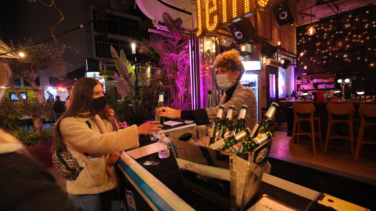 Jovens recebem drinks em bar após se vacinarem em Tel Aviv, Israel. 18/02/2021