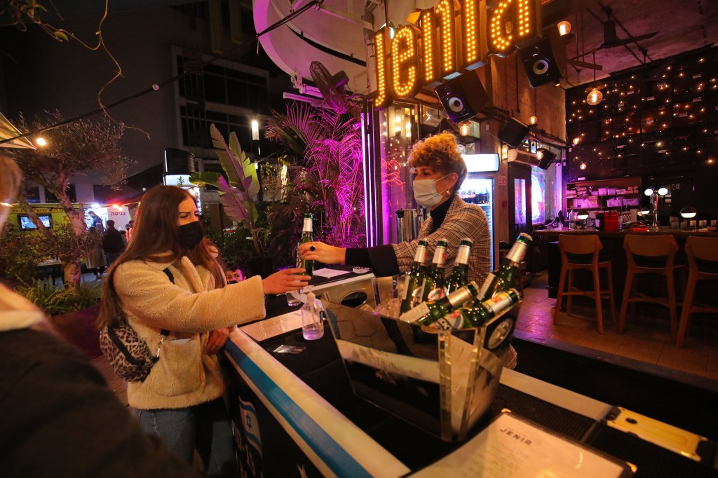 Jovens recebem drinks em bar após se vacinarem em Tel Aviv, Israel. 18/02/2021