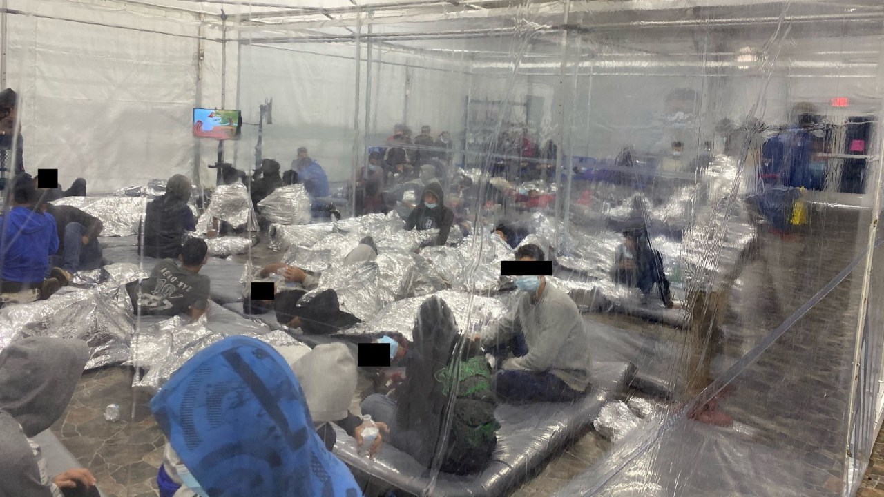 Migrantes lotam uma sala com paredes de lonas de plástico no centro de processamento temporário de Alfândega e Proteção de Fronteiras dos EUA em Donna, Texas.