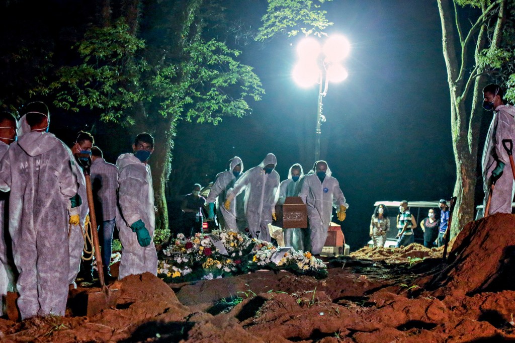Enterro noturno no cemitério de Vila Formosa, São Paulo - Cemetery workers carry a coffin during the first burial at night amid the coronavirus (COVID-19) pandemic at the Vila Formosa cemetery in Sao Paulo, Brazil, on March 25, 2021. - Brazil surpassed 100,000 new Covid-19 cases in one day on Thursday, adding another grim record in country where the pandemic has killed more than 300,000 people, the health ministry said. (Photo by Miguel SCHINCARIOL / AFP)