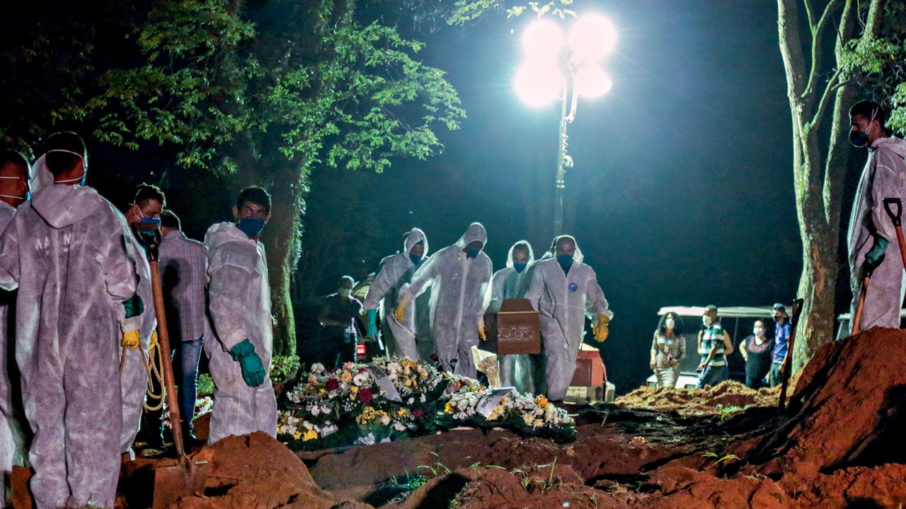 Enterro noturno no cemitério de Vila Formosa, São Paulo - Cemetery workers carry a coffin during the first burial at night amid the coronavirus (COVID-19) pandemic at the Vila Formosa cemetery in Sao Paulo, Brazil, on March 25, 2021. - Brazil surpassed 100,000 new Covid-19 cases in one day on Thursday, adding another grim record in country where the pandemic has killed more than 300,000 people, the health ministry said. (Photo by Miguel SCHINCARIOL / AFP)