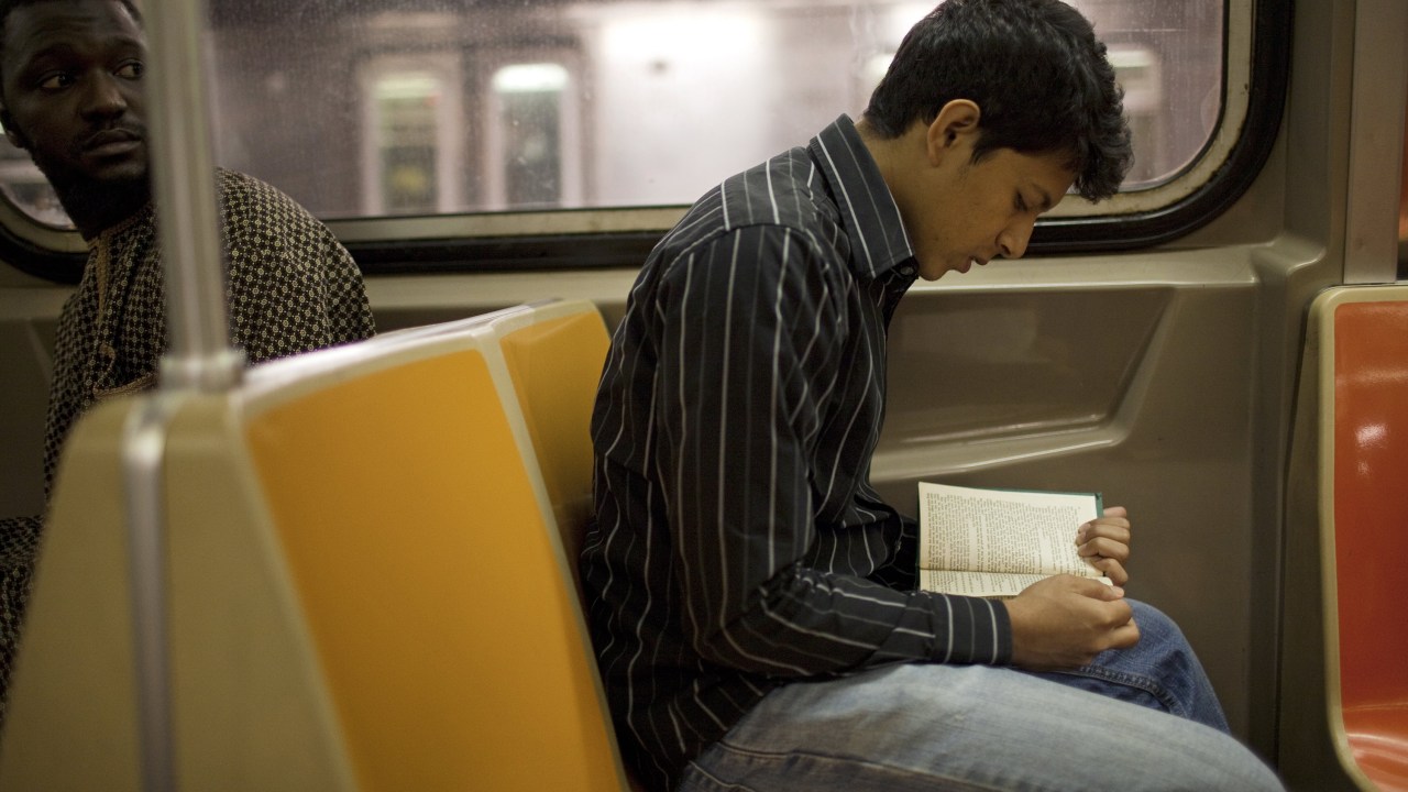 Jovem lendo livro no metrô