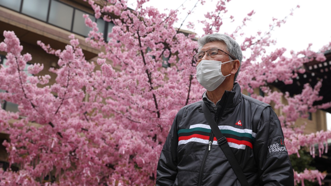 TOKYO, JAPAN - 2021/02/26: A man wearing a face mask seen at Sakura Jingu Shrine.The Cherry blossom also known as Sakura in Japan normally peaks in March or early April in spring. The Sakura is the National flower of Japan. (Photo by Stanislav Kogiku/SOPA Images/LightRocket via Getty Images)