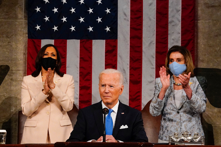 O presidente dos EUA, Joe Biden, em primeiro plano. Ao fundo, à esquerda, a vice, Kamala Harris, e, à direita, a Presidente da Câmara dos Representantes, Nancy Pelosi - 28/04/2021 -