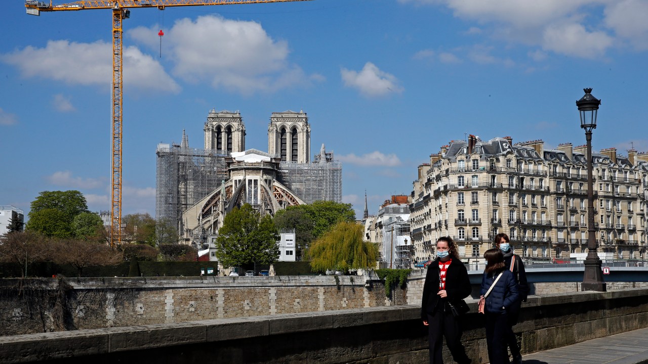 Pedestres com máscaras caminham perto da Notre Dame, em Paris. 13/04/2021