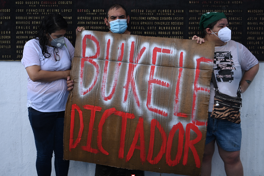 Demonstrators hold a sign reading “Bukele Dictator”, referring to Salvadoran Prsident Nayib Bukele