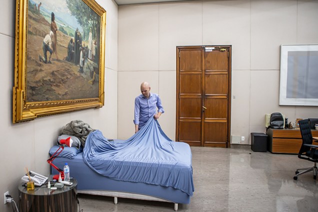 O prefeito arruma a cama que instalou na sede da prefeitura durante a pandemia do novo coronavírus -