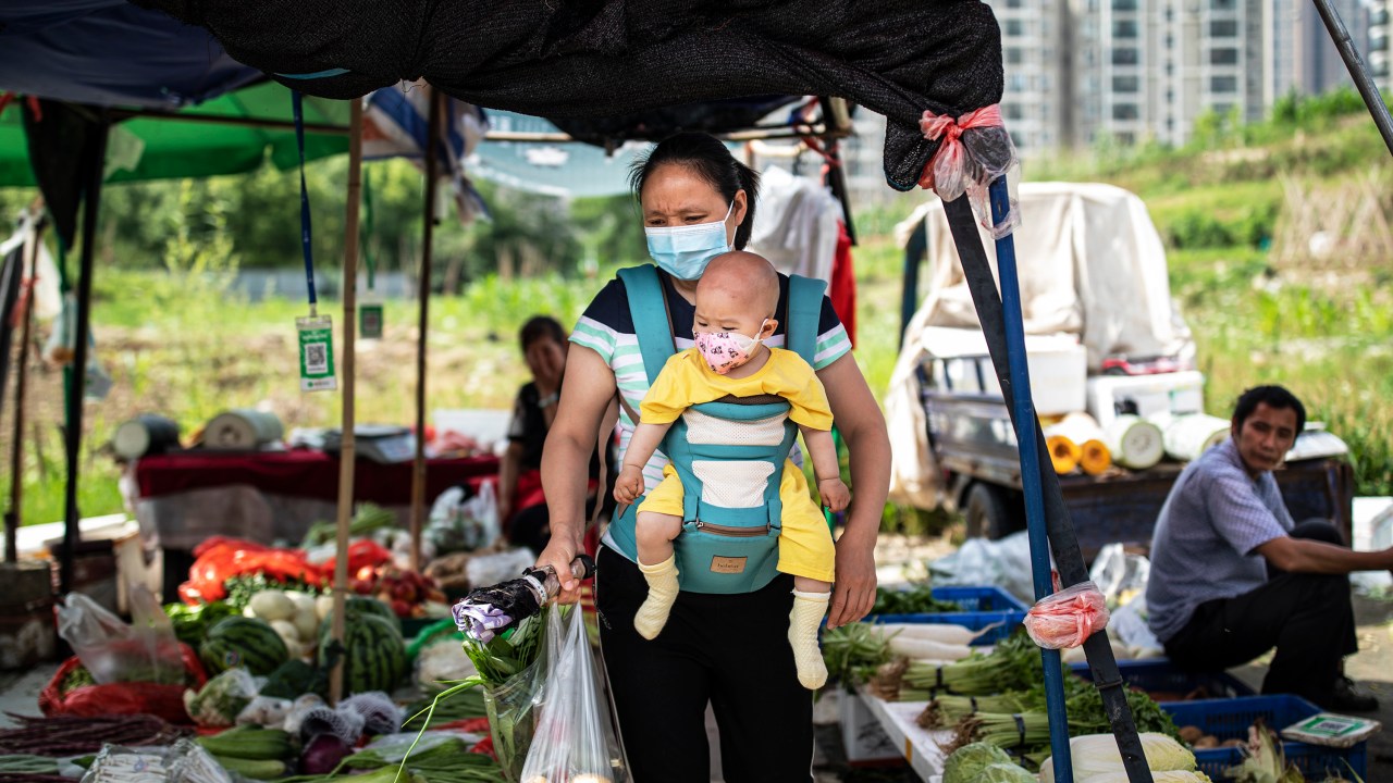 Mulher carrega o filho em mercado em Wuhan, China - 31/05/2021