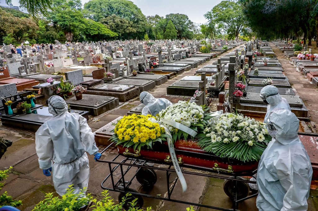 LUTO - Cemitério São João, em Porto Alegre: funcionários carregam caixão de vítima do vírus -