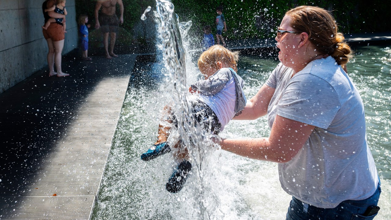 Mulher segura criança sob um chafariz em um parque de Washington, DC, em 28 de junho de 2021: temperaturas chegaram a 46.6ºC