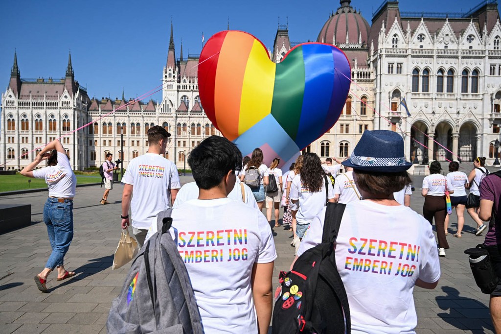 Ativistas usam camisetas com os dizeres "O amor é um direito humano" enquanto fazem voar um balão gigante de coração nas cores do arco-íris, durante ato para protestar contra uma nova lei em frente ao parlamento, em Budapeste -