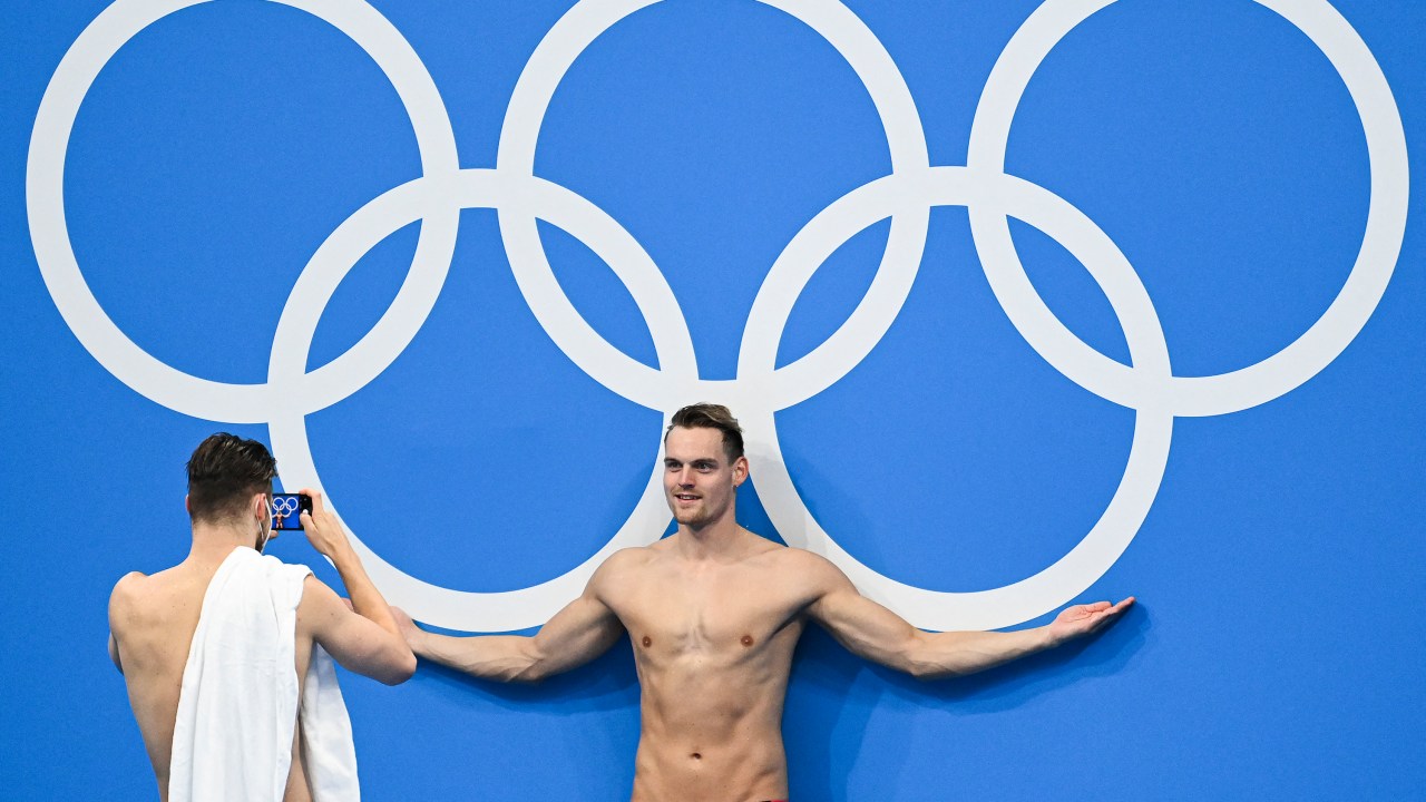 Atleta posa em frente aos anéis olímpicos durante uma sessão de treinamento de natação, no Centro Aquático de Tóquio -
