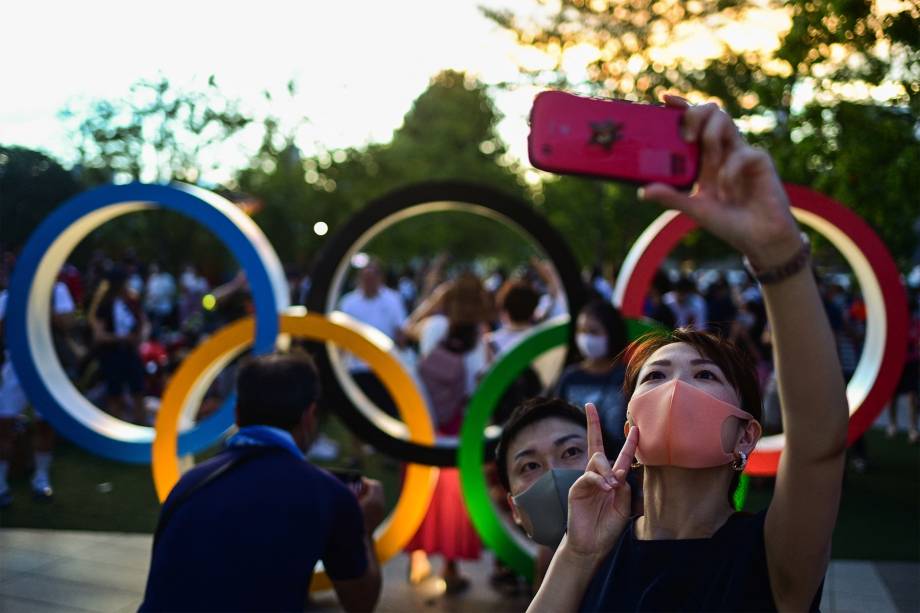 Pessoas fazem selfie em frente aos anéis Olímpicos durante a cerimônia de abertura das Olimpíadas 2020, em Tóquio -