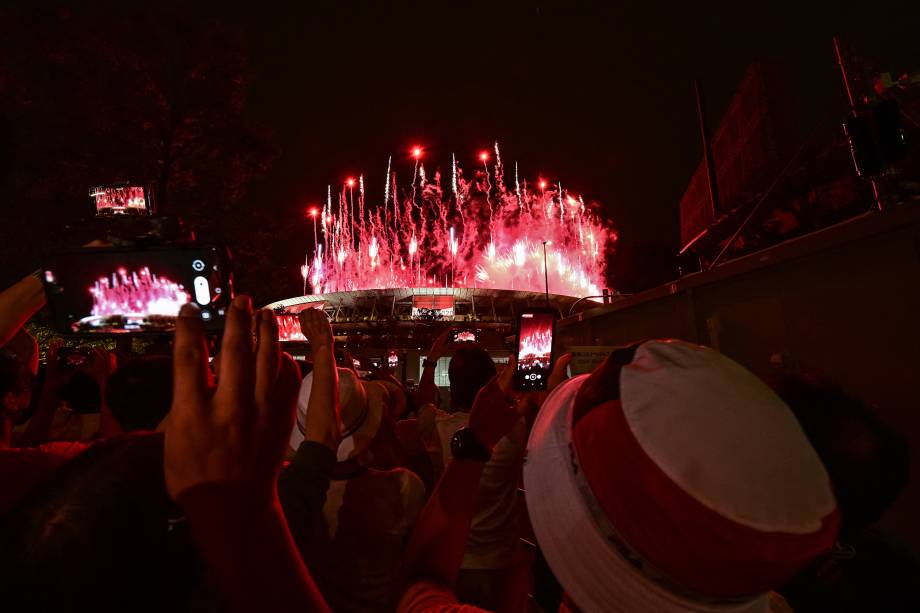 Apoiadores do lado de fora tiram fotos dos fogos de artifício iluminando o céu sobre o Estádio Olímpico -