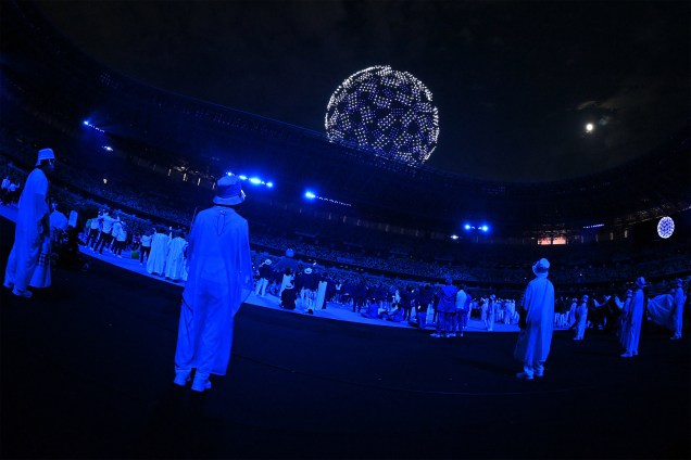 Atletas e voluntários olham drone no céu durante a cerimônia de abertura das Olimpíadas 2020, no Estádio Olímpico de Tóquio -