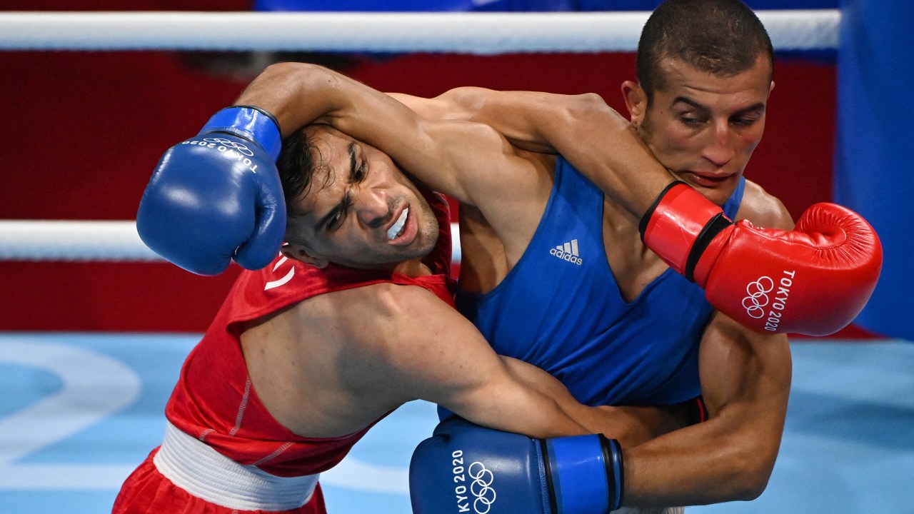 Iran's Daniyal Shahbakhsh (red) and Morocco's Mohamed Hamout fight during their men's feather (52-57kg) preliminaries boxing match during the Tokyo 2020 Olympic Games at the Kokugikan Arena in Tokyo on July 24, 2021. (Photo by Luis ROBAYO / AFP)