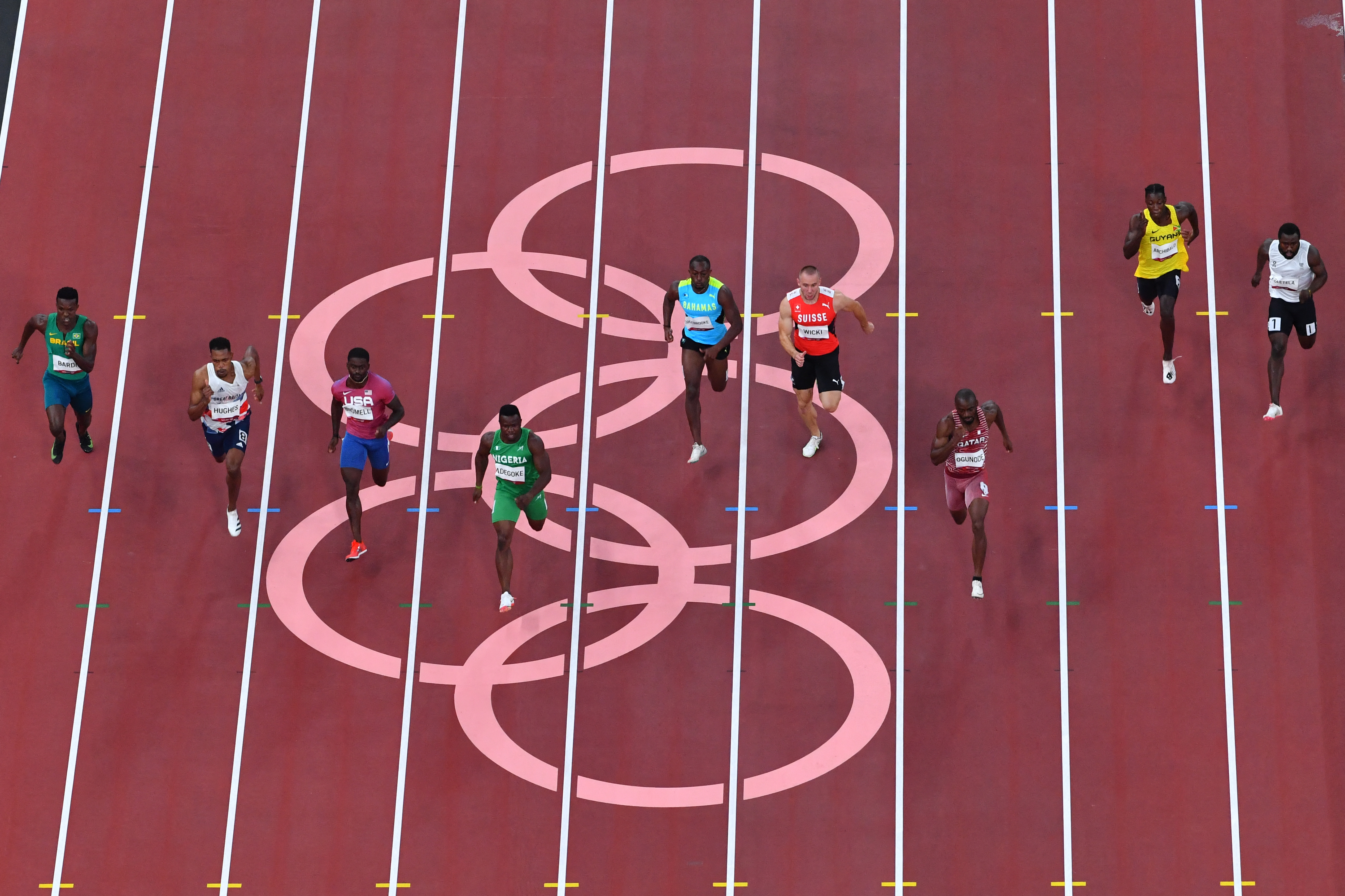 Trayvon Bromell, Nigeria's Enoch Adegoke, Bahamas's Samson Colebrooke, Switzerland's Silvan Wicki, Qatar's Femi Ogunode, Guyana's Emanuel Archibald and Refugee Olympic Team's Dorian Keletela compete in the men's 100m heats during the Tokyo 2020 Olympic Games at the Olympic Stadium in Tokyo on July 31, 2021. (Photo by Antonin THUILLIER / AFP)