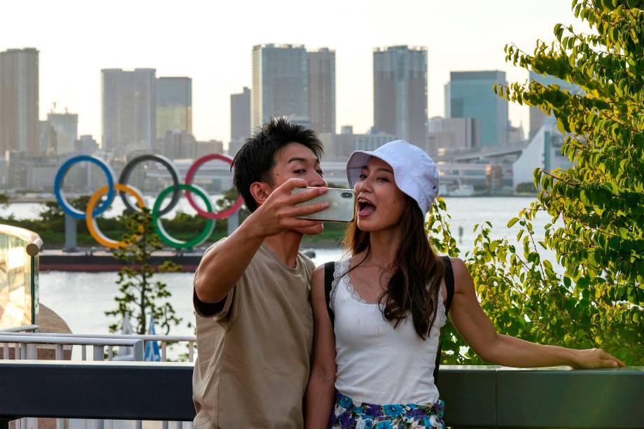 Casal faz selfie em frente aos anéis Olímpicos em Odaiba durante as Olimpíadas de Tóquio -