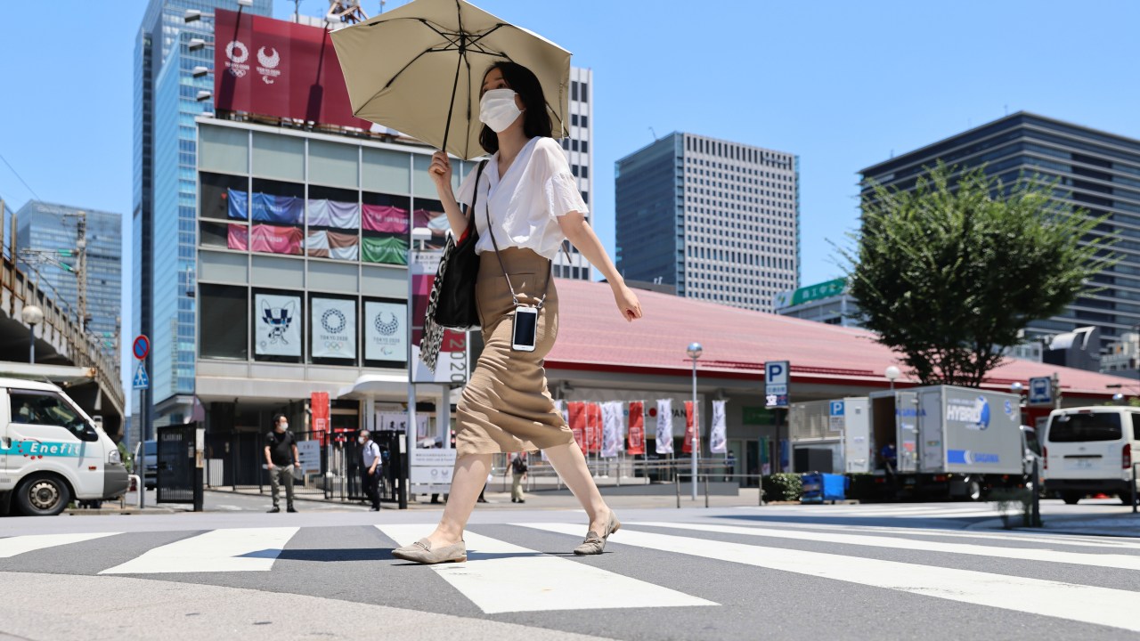Mulher se protege do calor em Tóquio com sombrinha: temperaturas extremas